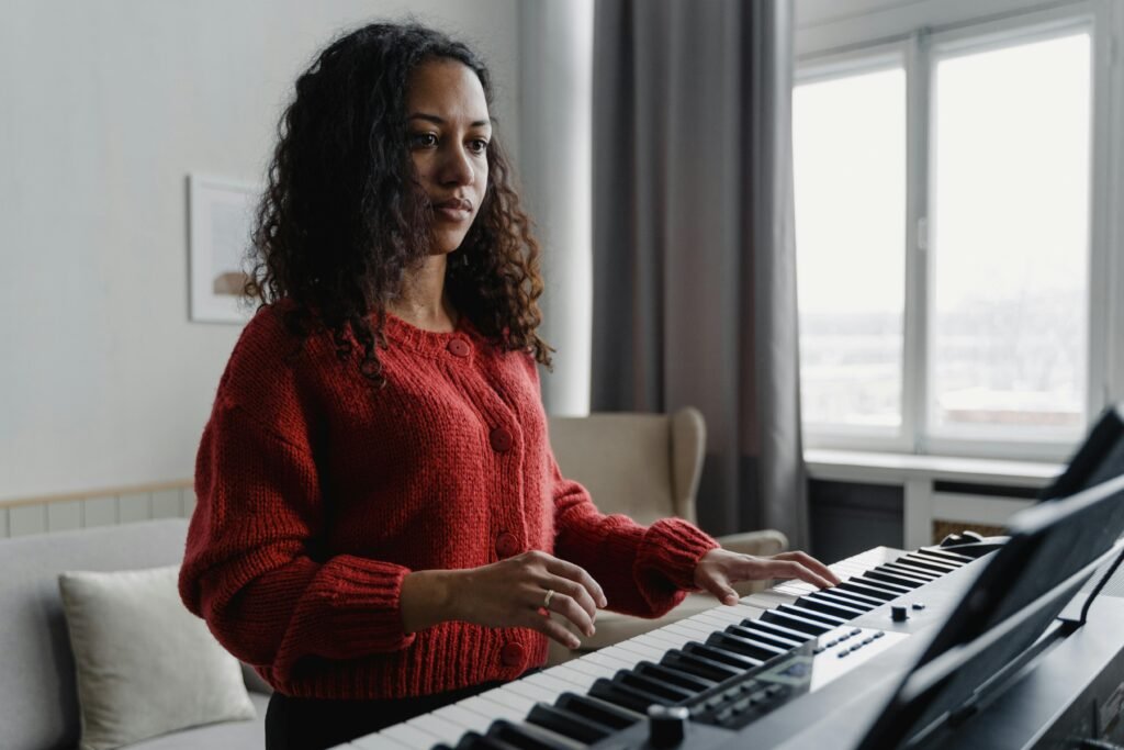 pexels-photo-6671948-6671948 Woman in red sweater focused on playing the piano practicing what she learned in piano lessons