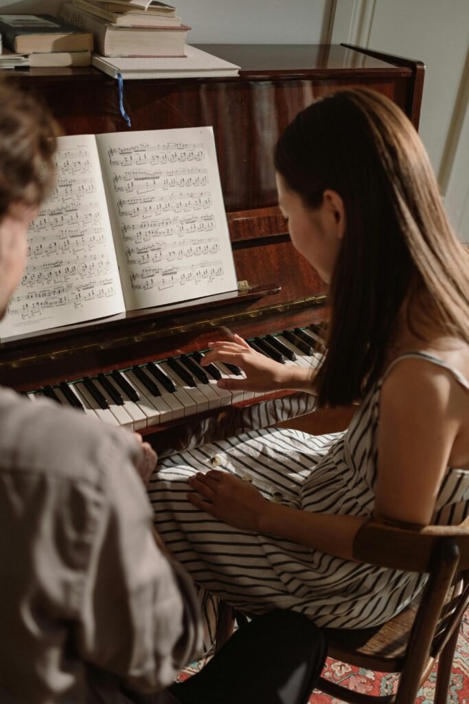 pexels-photo-10254571-10254571 Woman in striped dress plays piano in a music education class, accompanied by another person.