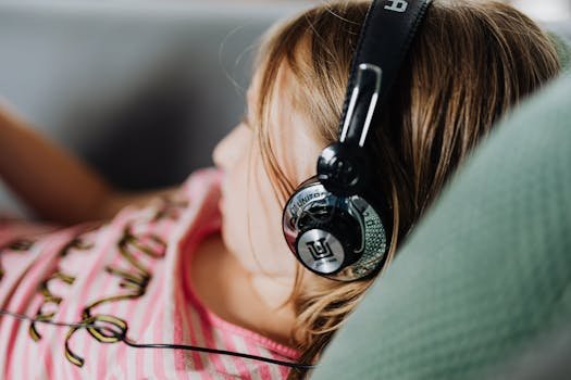 A young girl enjoys music using headphones while lounging comfortably indoors.