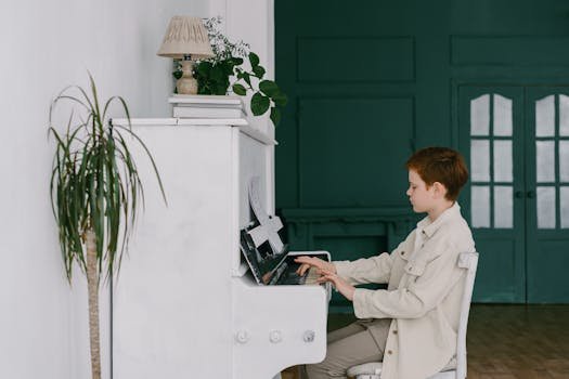 Young boy playing a piano indoors with plants surrounding, showcasing musical talent and lifestyle.