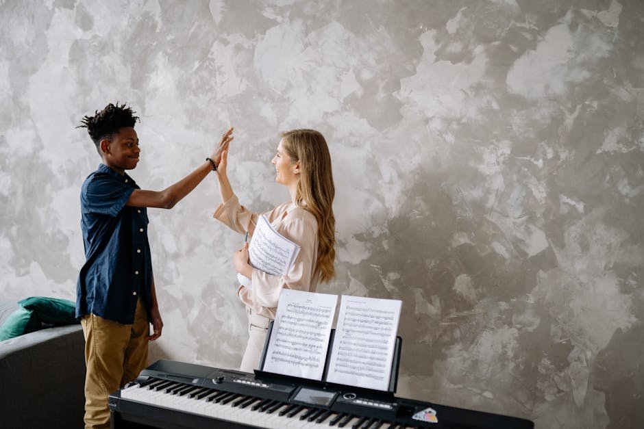 A student and teacher share a high-five during a piano lesson, after he meets his piano goals.