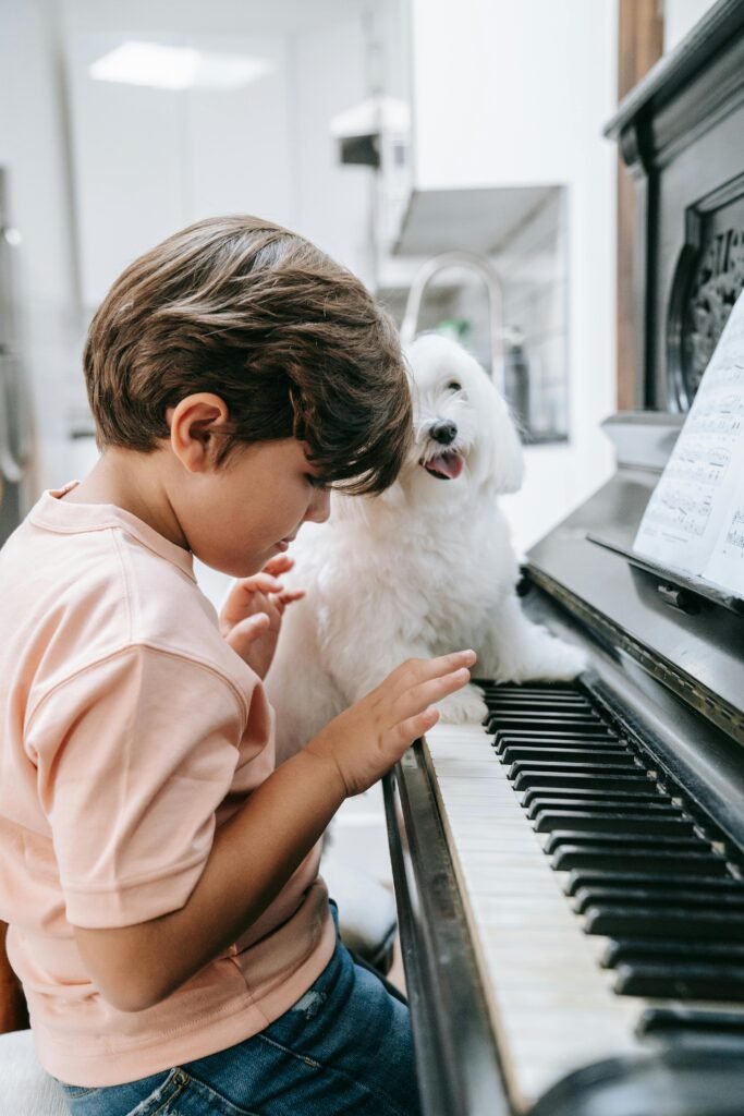 pexels-photo-9428217-9428217 Young boy plays the piano with his dog; music education.